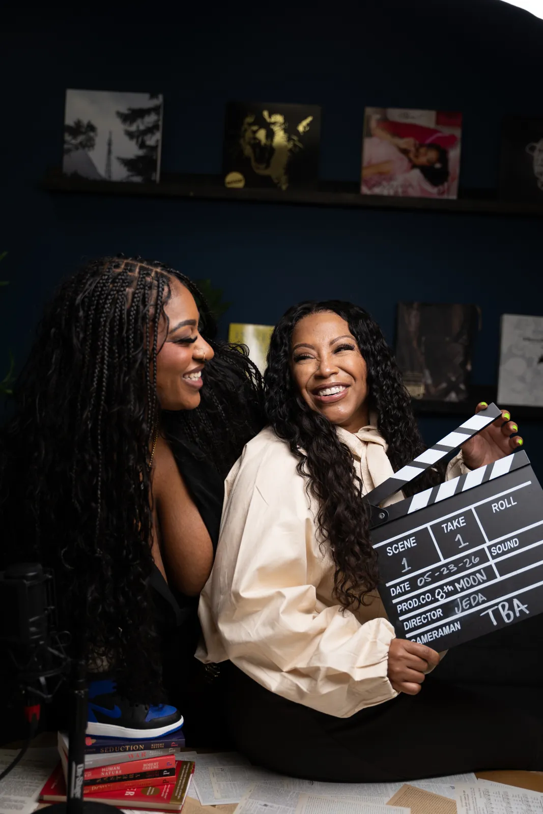 Malaysia Genjiia and Lauresha Z. Hawkins laughing while holding an 8th Moon clapperboard in the studio